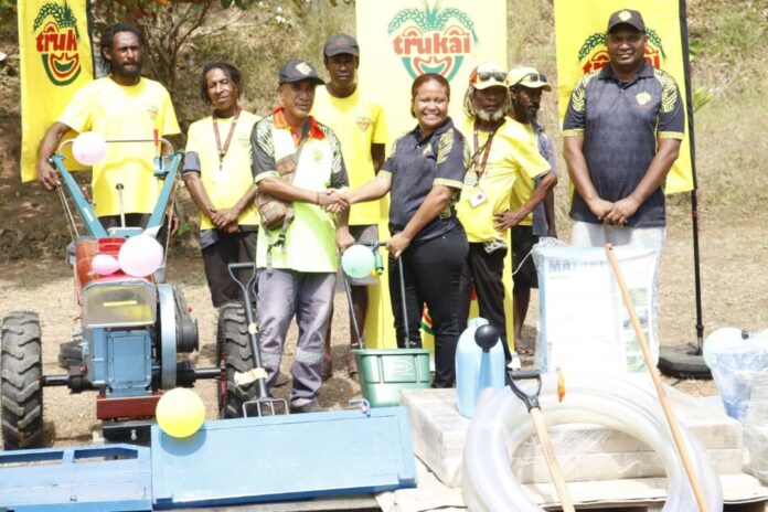 The Agricuture Manager for Trukai Ms: Aina Davis with PAU site Manager Thomas Tetu (both in uniform) officially presenting the Village Sustainability Kit to John. Photo By Miriam Malawa